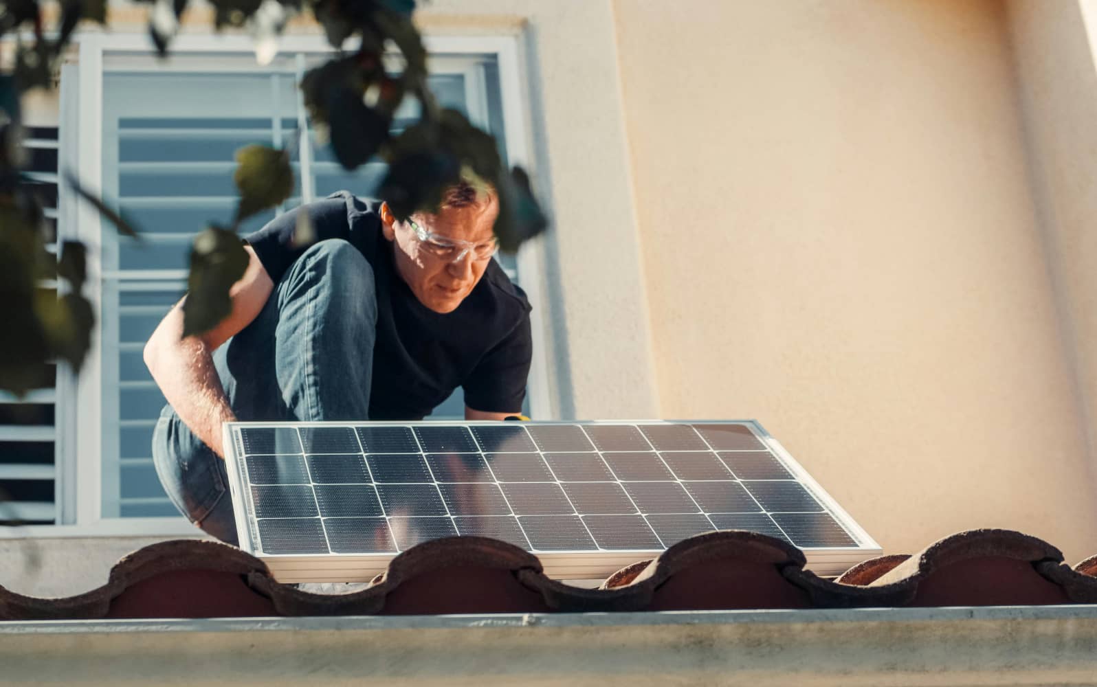 A man installing a solar panel on a roof