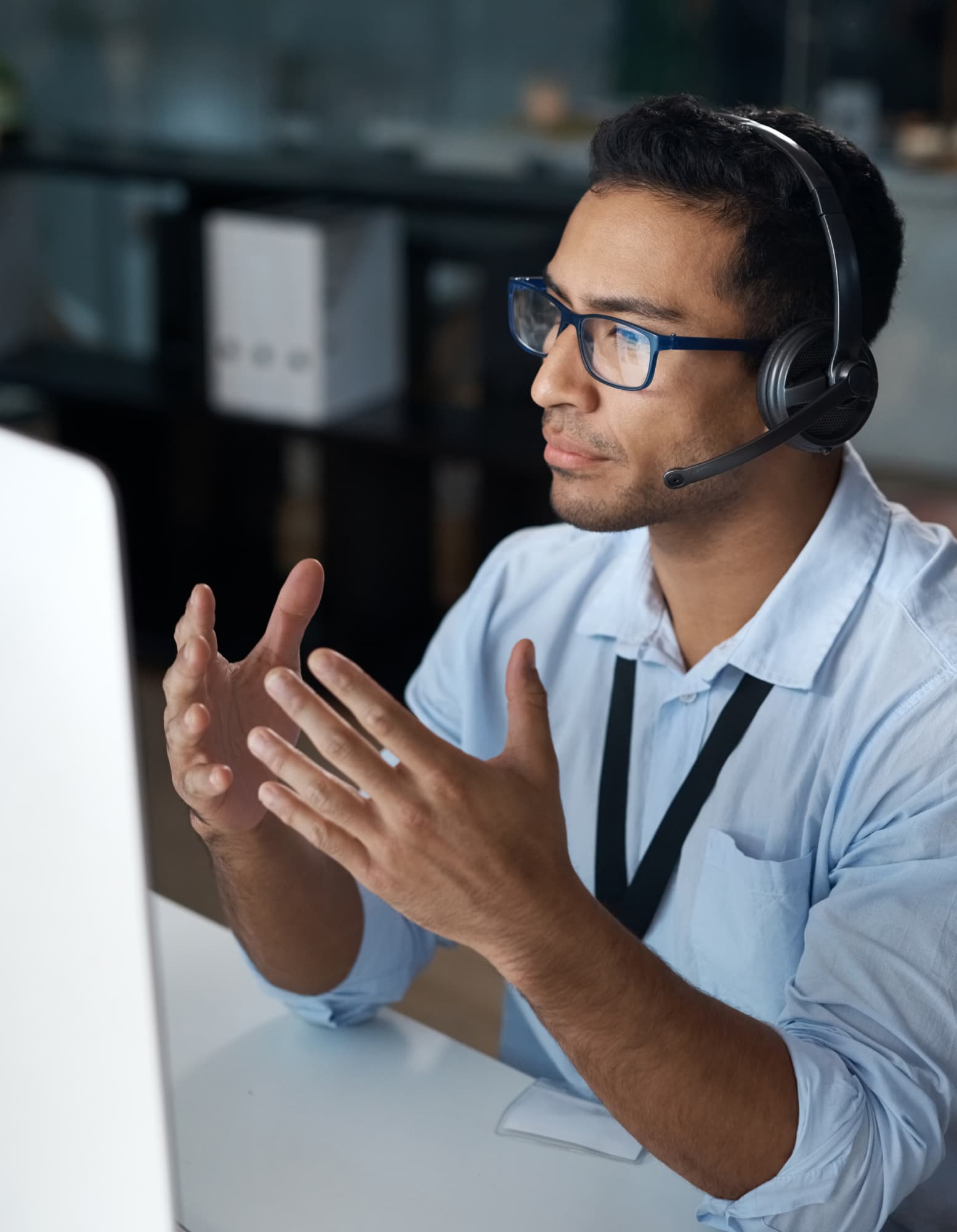 A car salesperson wearing a headset at a computer while speaking with a customer