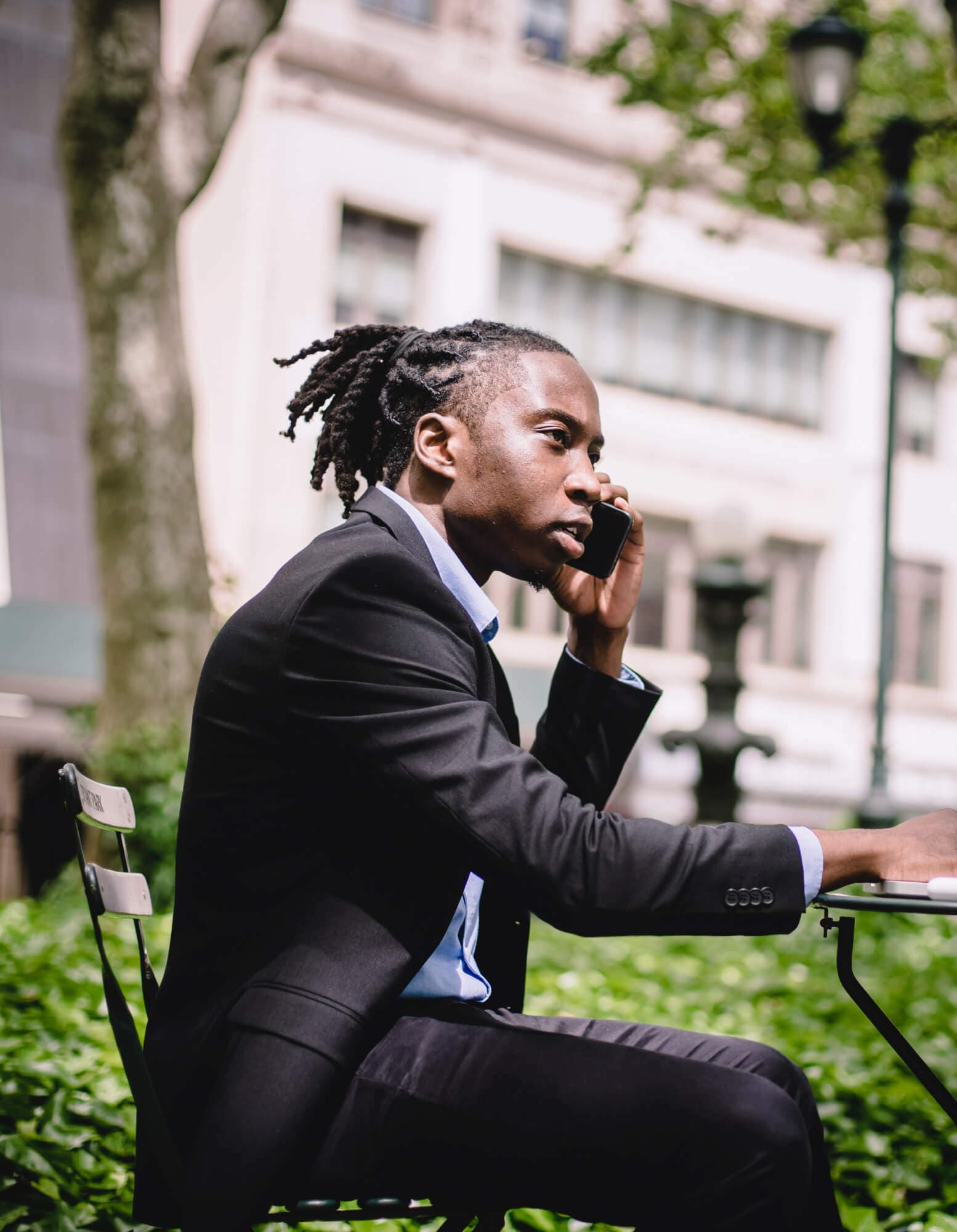 A man sitting outside in a park, on a phone call