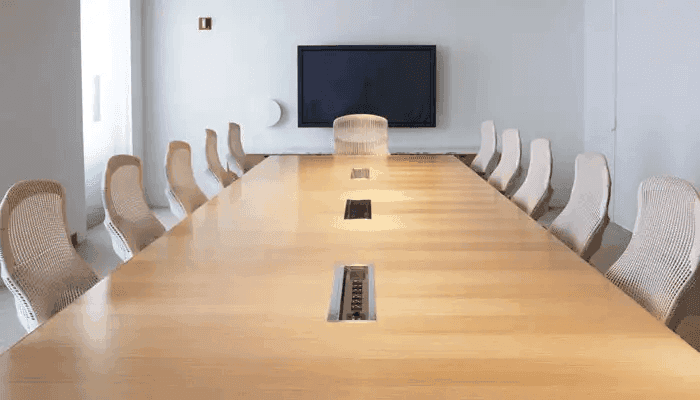 A boardroom conference room setup where the central table has power sockets along the center